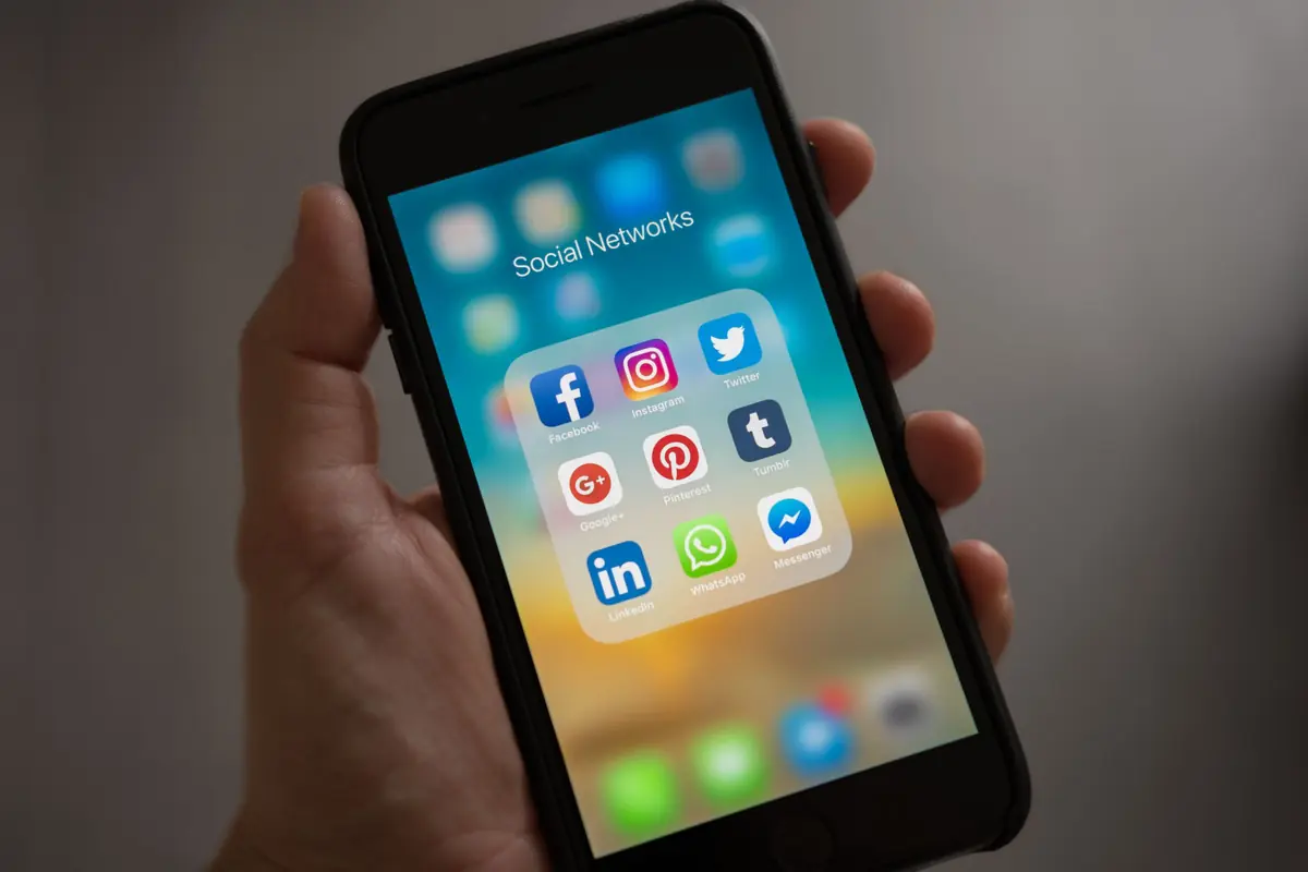Main qui tient un smartphone ouvert sur les applications de réseaux sociaux