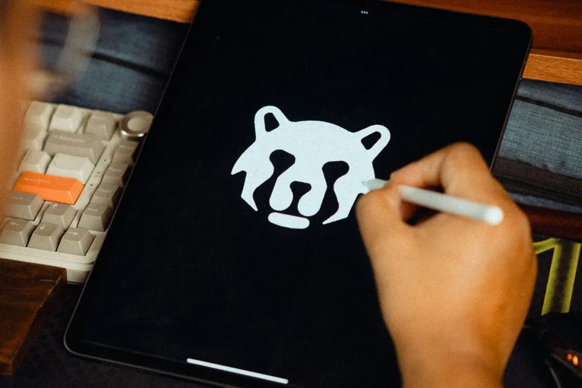 Main qui dessine un logo au stylet sur une tablette